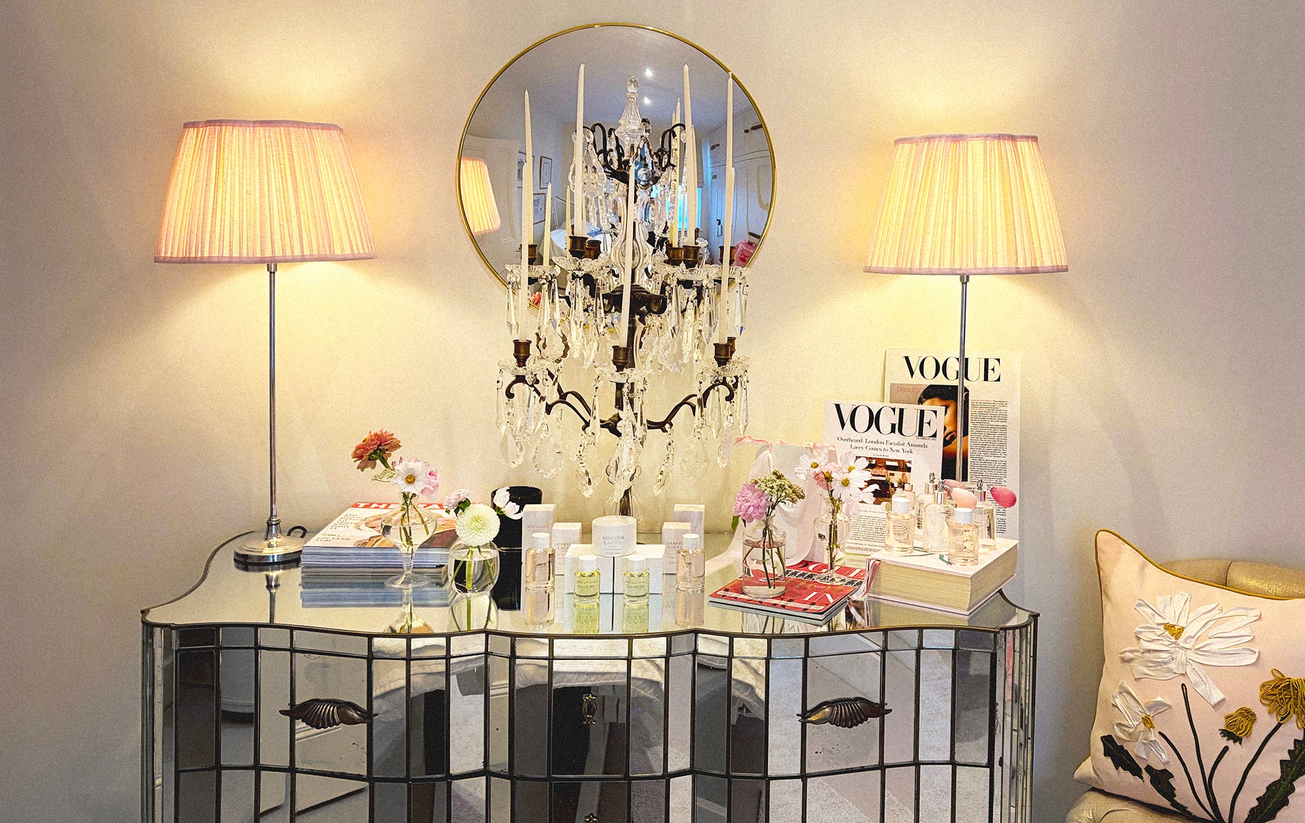 The Amanda Lacey atelier: a mirrored console under a crystal candelabra, her formulations and press laid out beside pink silk lampshades